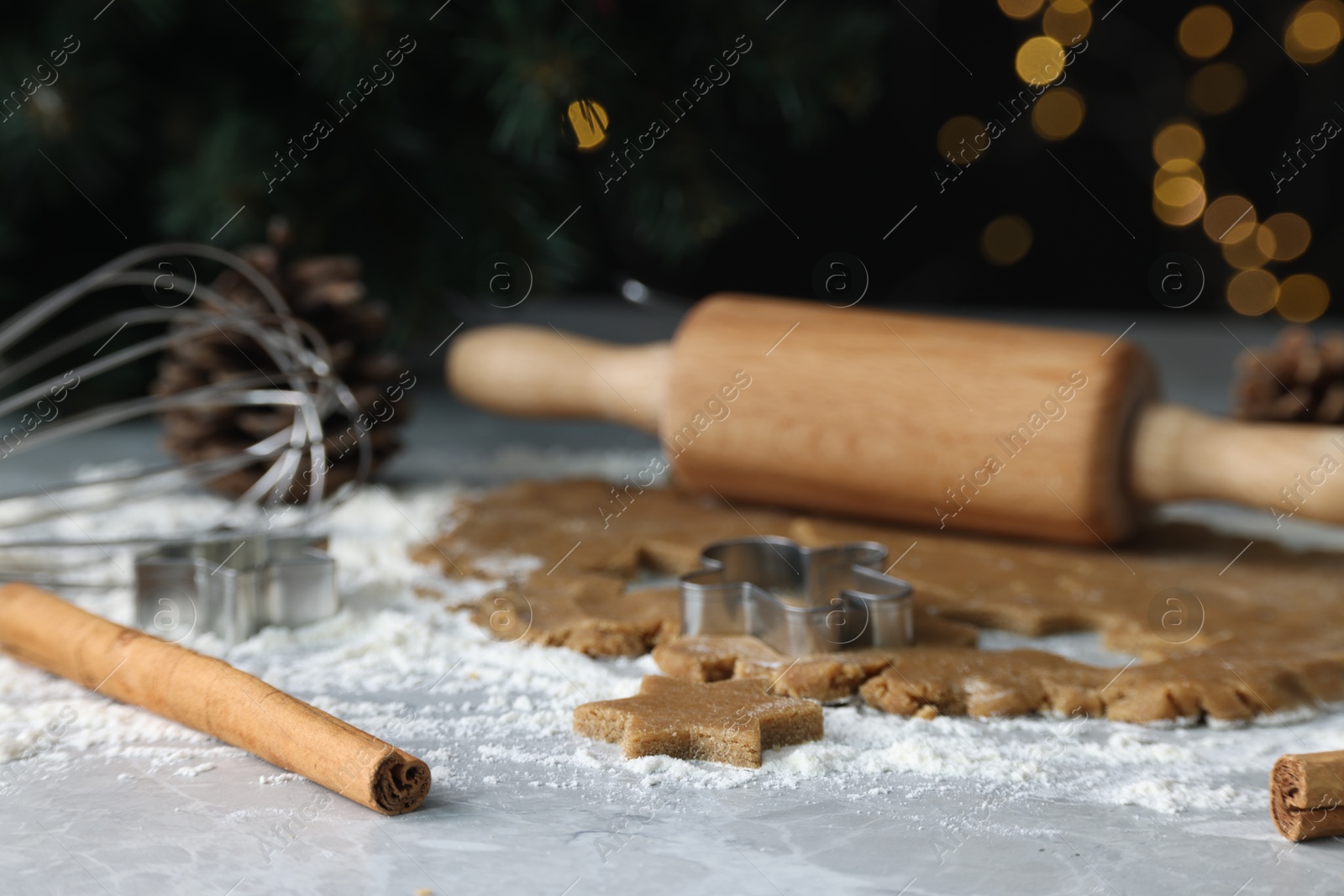 Photo of Raw dough, cookie cutters, pine cone, whisk and rolling pin on grey table, closeup