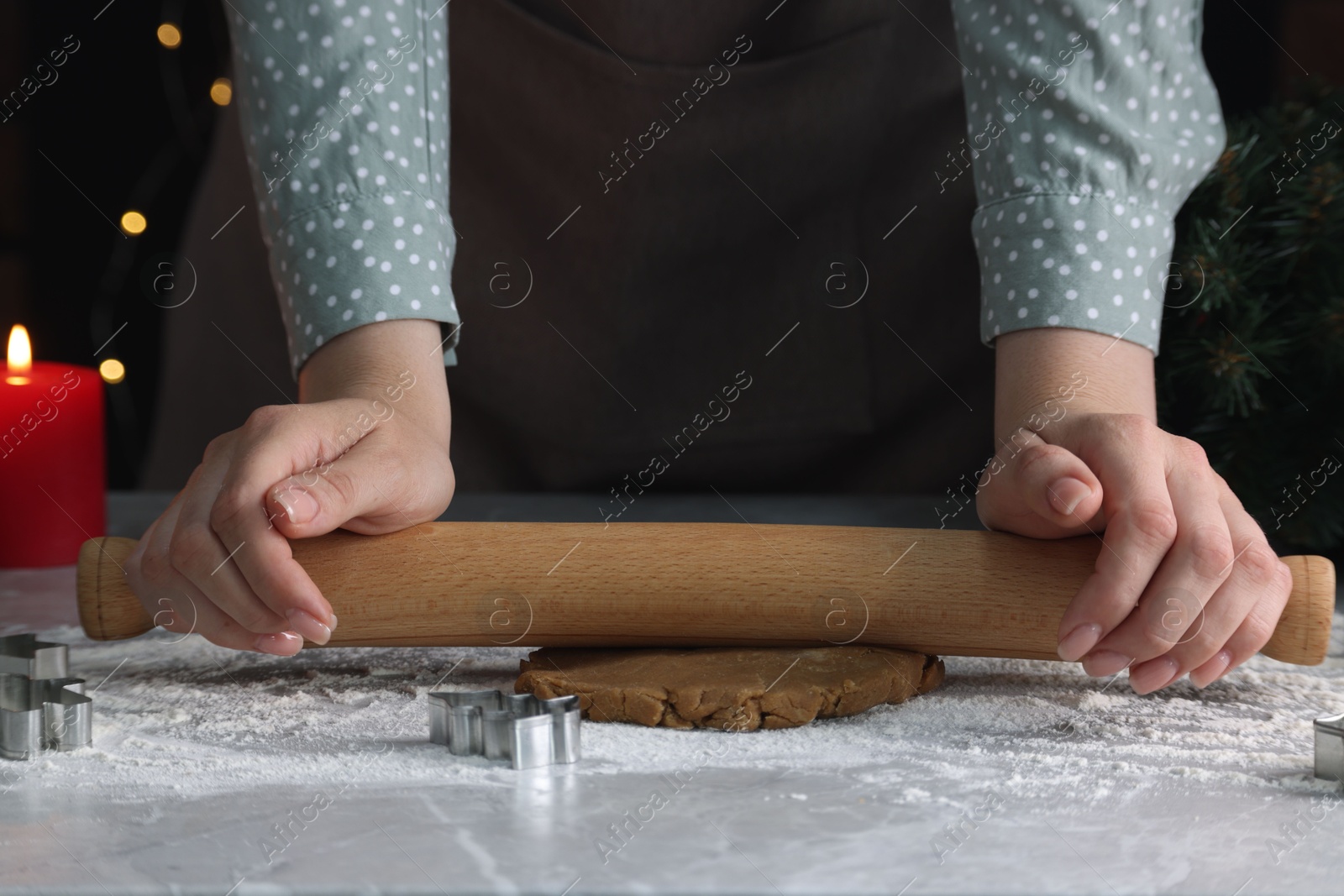 Photo of Woman rolling out dough for cookies at light grey marble table, closeup