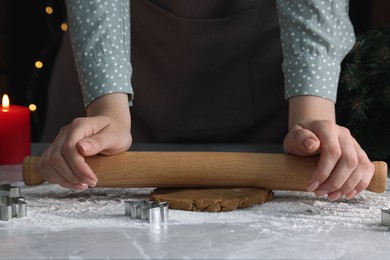 Photo of Woman rolling out dough for cookies at light grey marble table, closeup