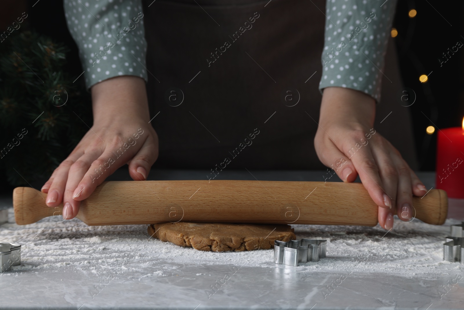 Photo of Woman rolling out dough for cookies at light grey marble table, closeup