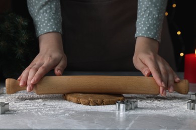 Woman rolling out dough for cookies at light grey marble table, closeup