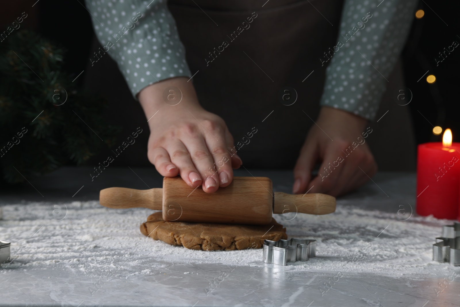 Photo of Woman rolling out dough for cookies at light grey marble table, closeup