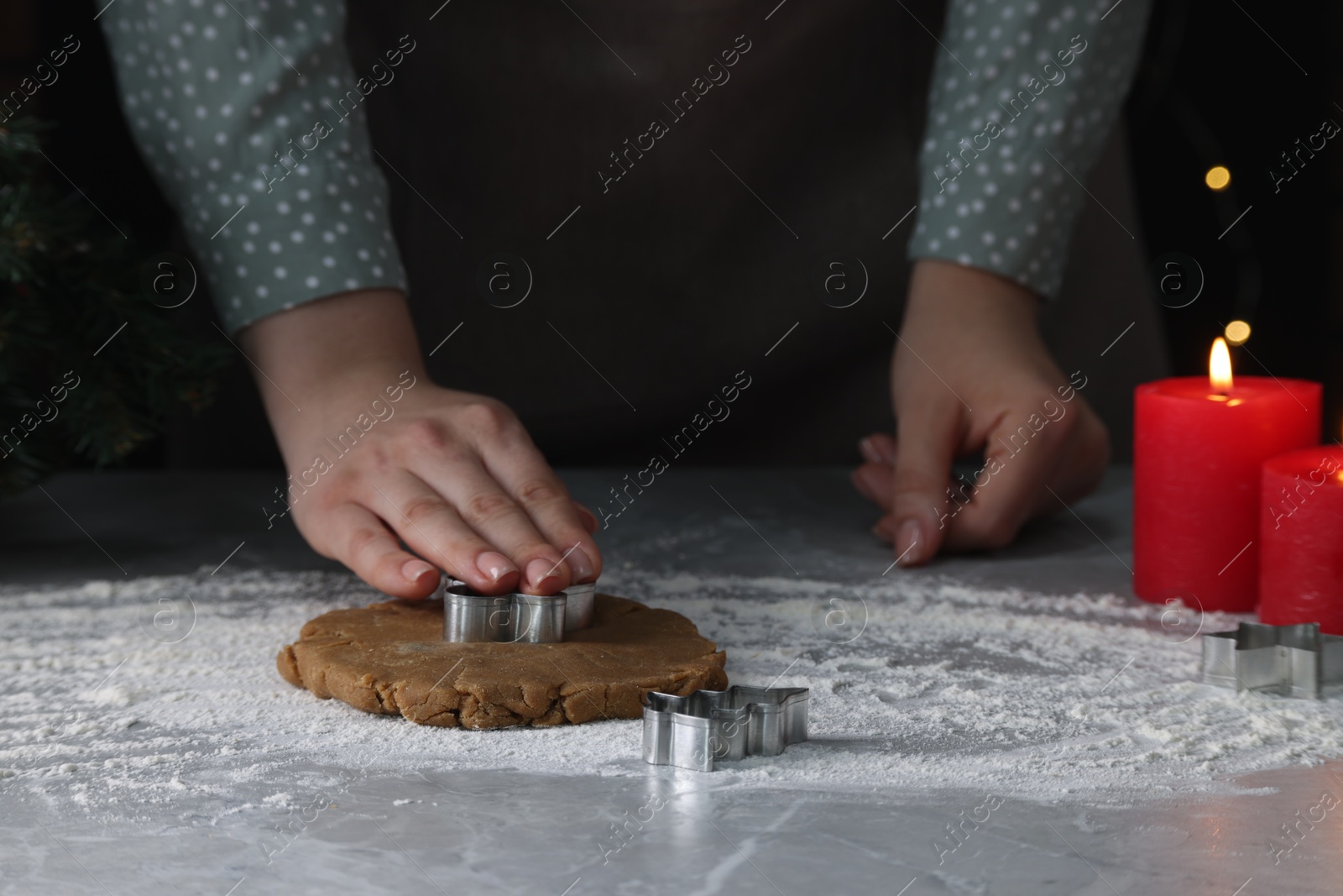 Photo of Woman cutting dough with cookie cutter at light grey marble table, closeup