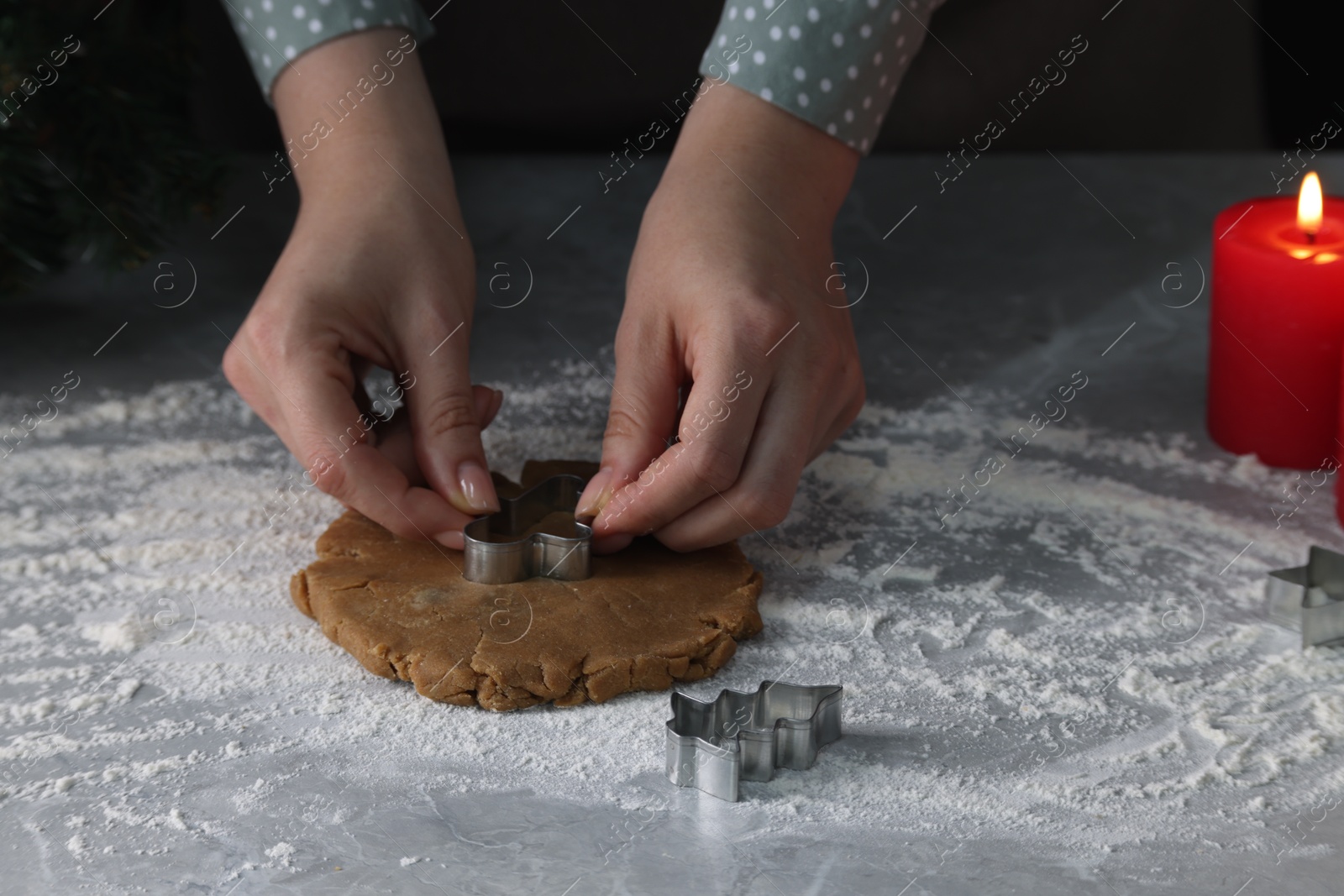 Photo of Woman cutting dough with cookie cutter at light grey marble table, closeup