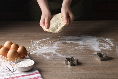 Woman kneading dough for cookies at wooden table, closeup