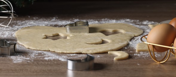 Photo of Raw dough, cookie cutters and egg on wooden table