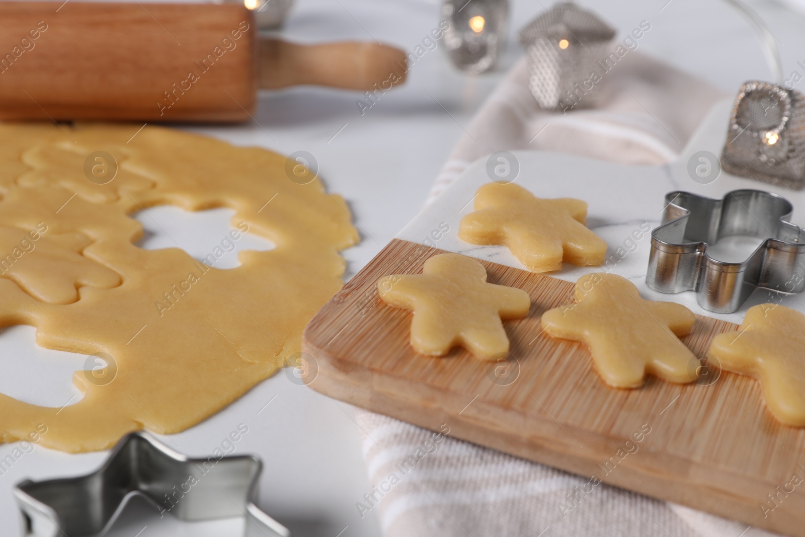 Photo of Making cookies. Board with raw dough and cutters on white table