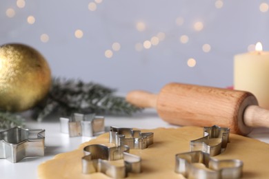 Photo of Making cookies. Raw dough and cutters on white table