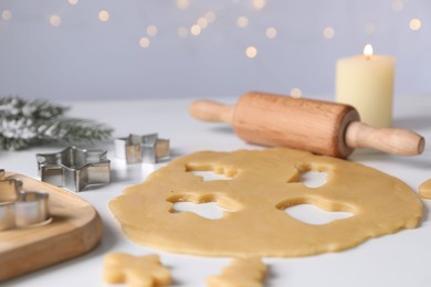 Photo of Making cookies. Raw dough, rolling pin and cutters on white table