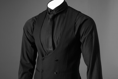 Male mannequin dressed in stylish black suit on grey background