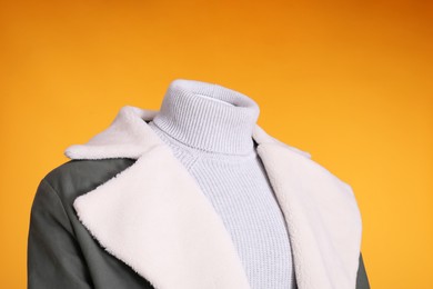 Photo of Female mannequin dressed in stylish jacket and turtleneck on orange background