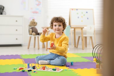 Photo of Cute little boy playing with math game Fishing for Numbers on puzzle mat in kindergarten