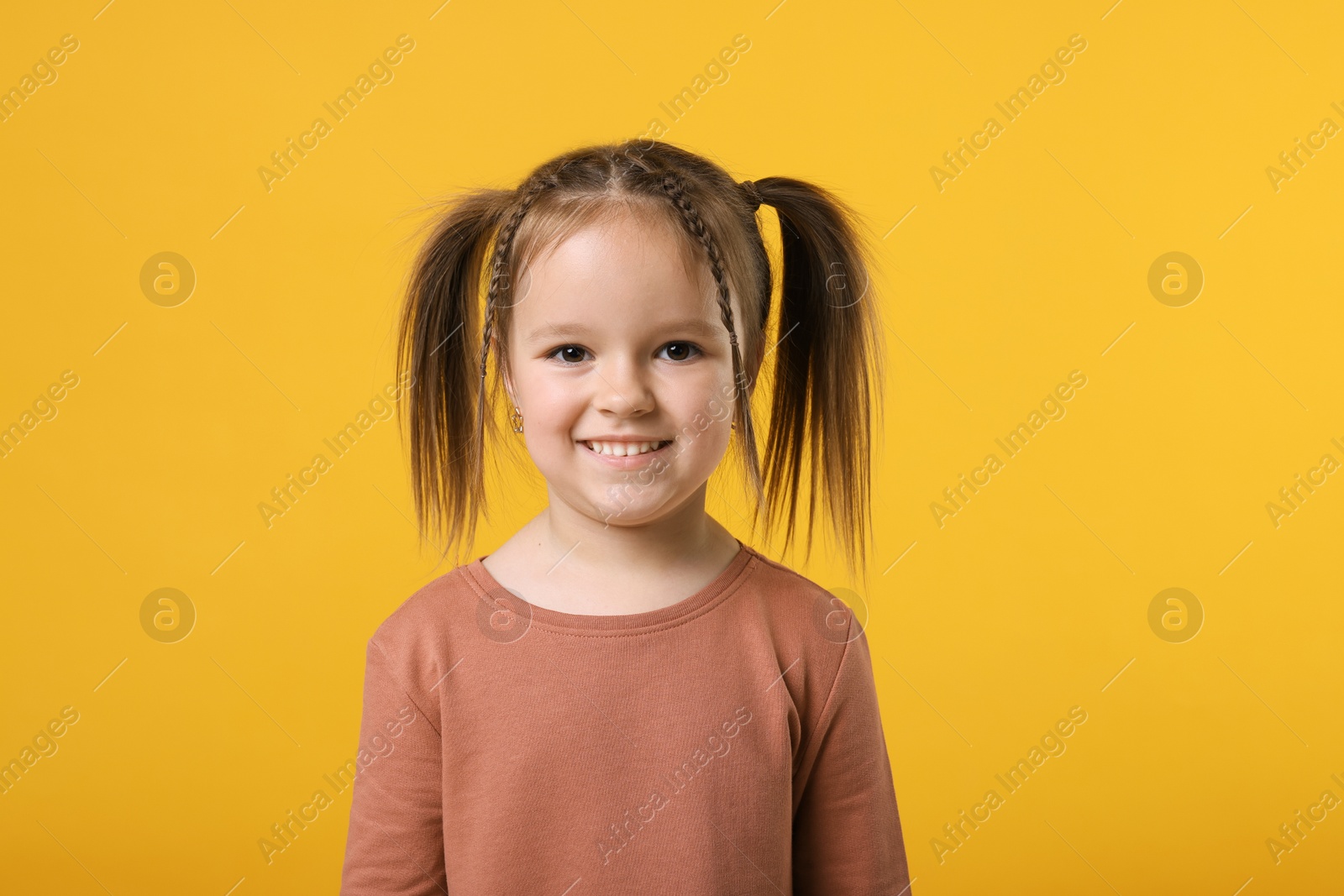 Photo of Portrait of cute little girl on orange background