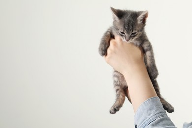 Photo of Woman with cute fluffy kitten on light grey background, closeup. Space for text