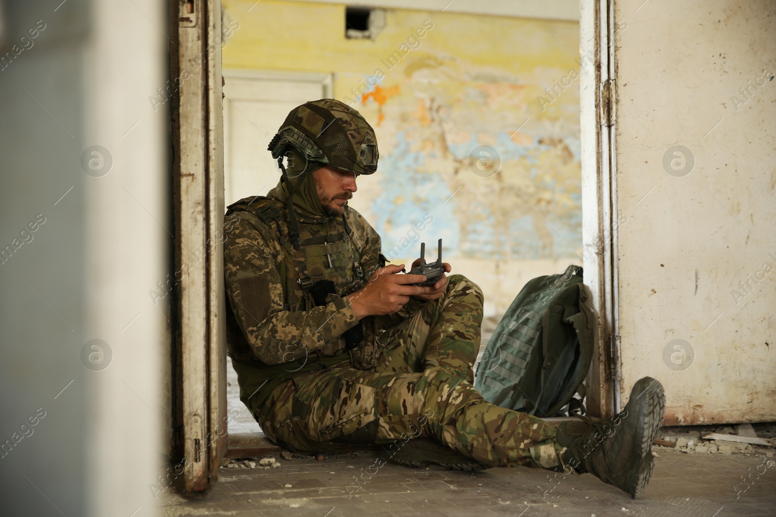 Photo of Military mission. Soldier in uniform with drone controller inside abandoned building