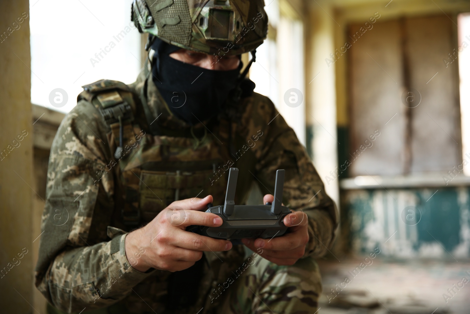 Photo of Military mission. Soldier in uniform with drone controller inside abandoned building, selective focus