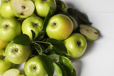 Photo of Fresh ripe green apples with leaves on white wooden table, closeup. Space for text