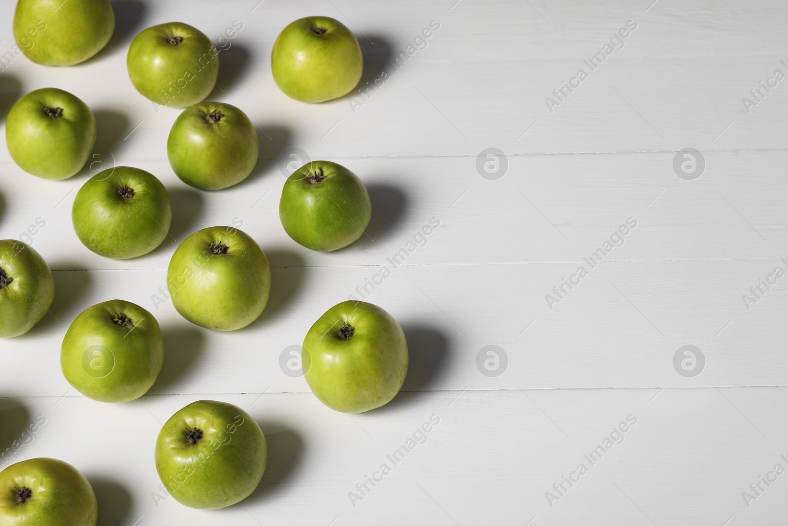 Photo of Fresh ripe green apples on white wooden table. Space for text