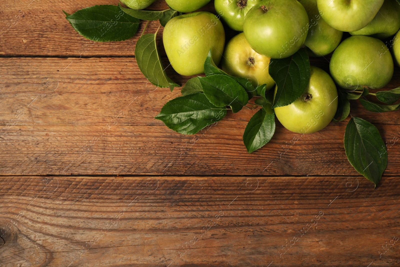 Photo of Ripe green apples with leaves on wooden table, flat lay. Space for text