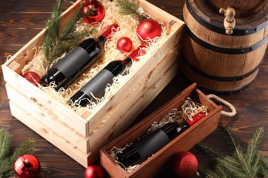 Photo of Wooden boxes with bottles of wine, fir twigs, barrel and red Christmas balls on table