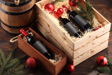 Photo of Wooden boxes with bottles of wine, fir twigs, barrel and red Christmas balls on table