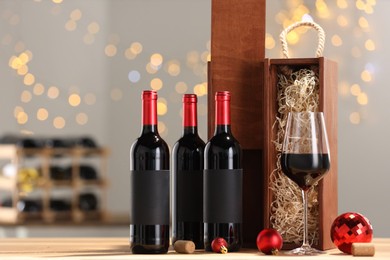 Photo of Bottles of wine, glass, wooden gift boxes, corks and red Christmas balls on table, space for text