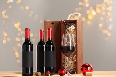 Photo of Bottles of wine, glass, wooden gift boxes, corks and red Christmas balls on table