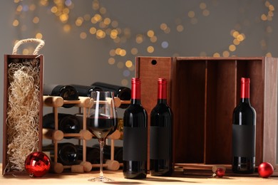 Photo of Bottles of wine, glass, wooden gift boxes, barrel corks and red Christmas balls on table