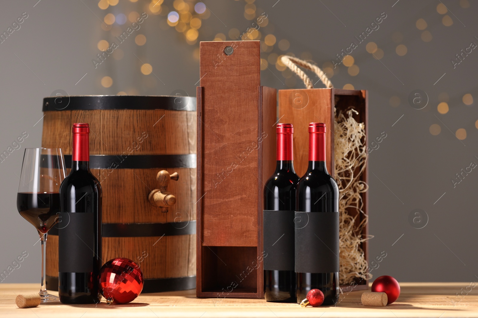 Photo of Bottles of wine, glass, wooden gift boxes, barrel corks and red Christmas balls on table