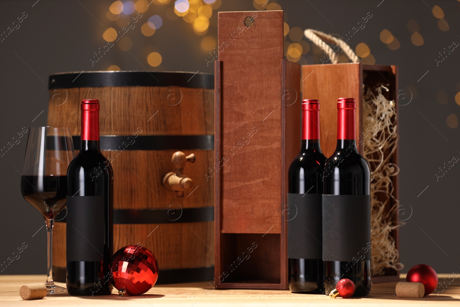 Photo of Bottles of wine, glass, wooden gift boxes, barrel corks and red Christmas balls on table