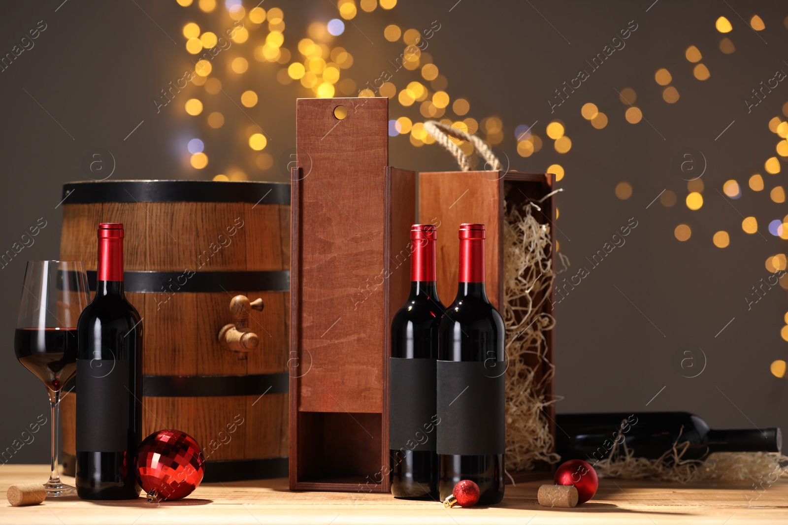 Photo of Bottles of wine, glass, wooden gift boxes, barrel corks and red Christmas balls on table