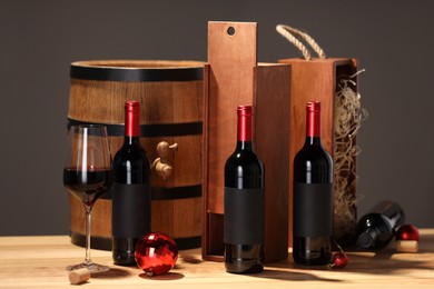 Photo of Bottles of wine, glass, wooden gift boxes, barrel corks and red Christmas balls on table