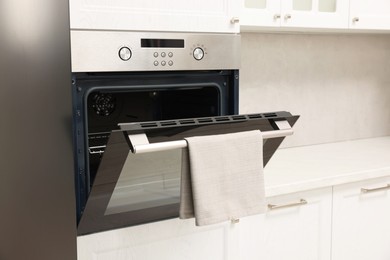 Open electric oven with towel in kitchen. Cooking appliance