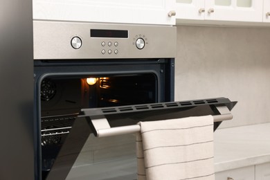 Photo of Open electric oven with towel in kitchen. Cooking appliance