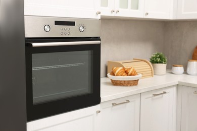 Photo of Electric oven and croissants in kitchen. Cooking appliance