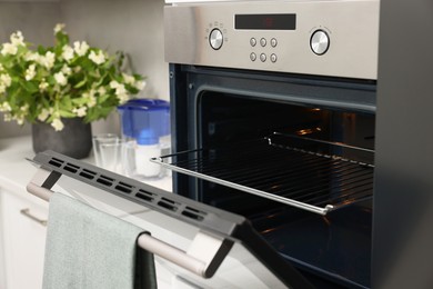 Photo of Open electric oven with towel in kitchen. Cooking appliance