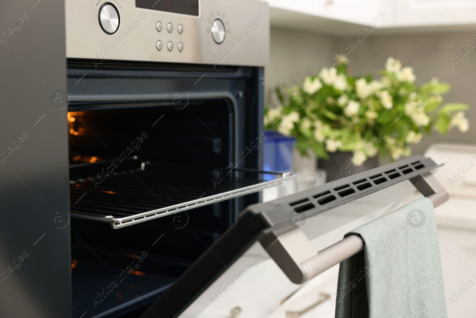 Photo of Open electric oven with towel in kitchen. Cooking appliance