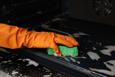 Woman cleaning oven with sponge, closeup view