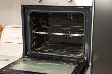 Open electric oven covered with cleaning foam in kitchen