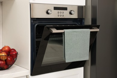 Photo of Open electric oven with towel in kitchen. Cooking appliance