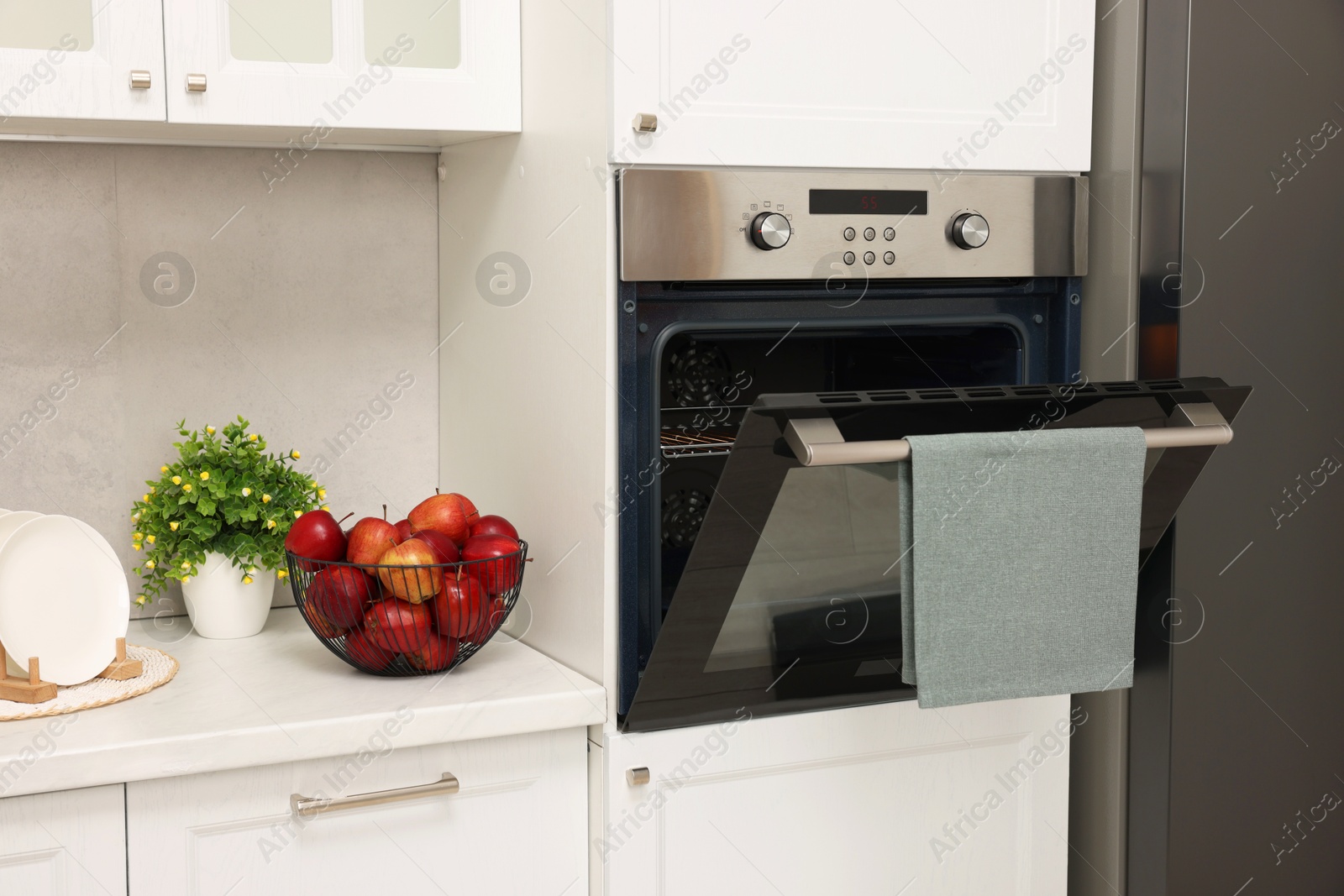 Photo of Open electric oven with towel in kitchen. Cooking appliance