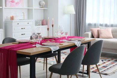 Photo of Beautiful table setting with pink accent and chairs in dining room