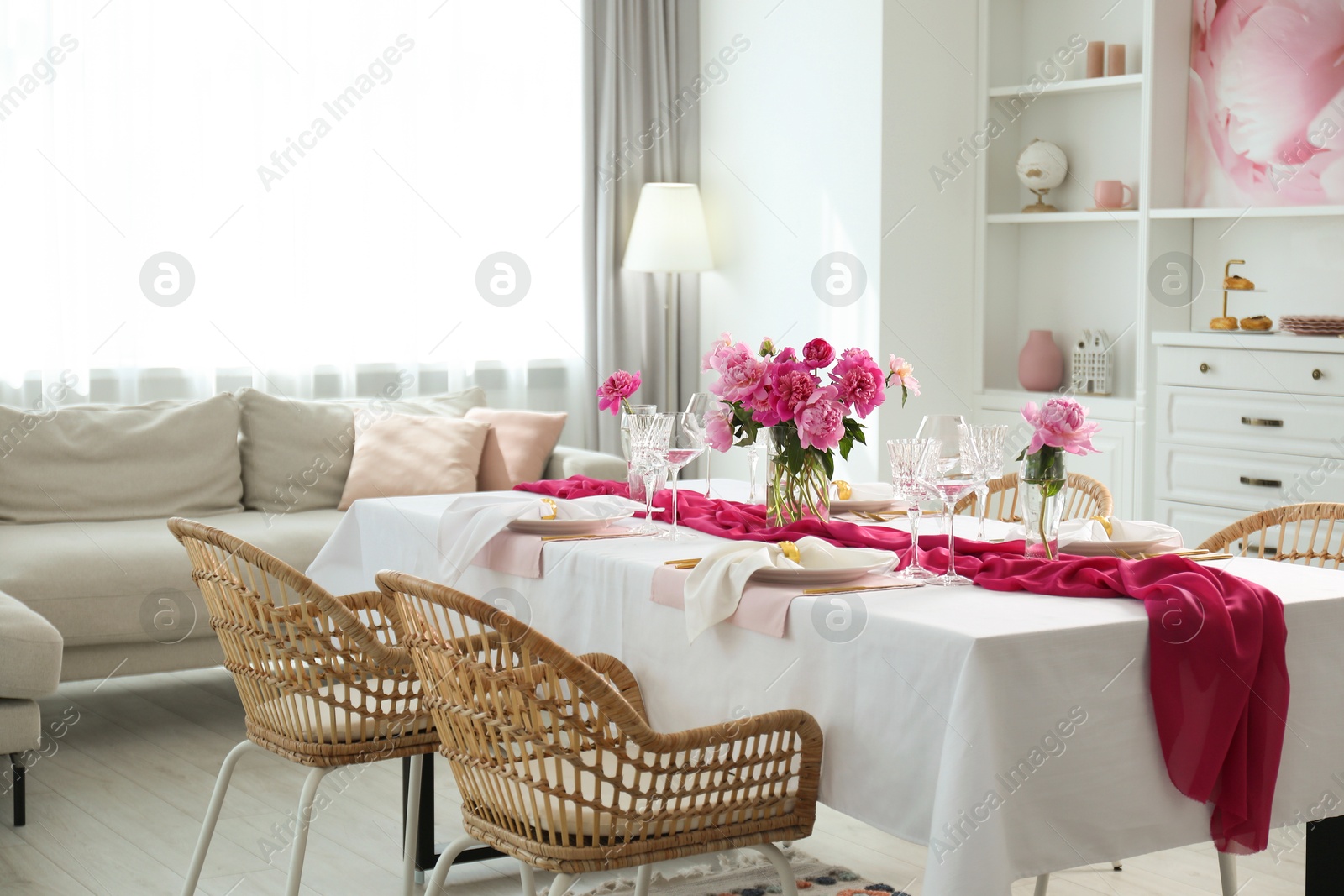 Photo of Beautiful table setting with flowers and rattan chairs in dining room