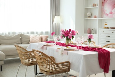 Beautiful table setting with flowers and rattan chairs in dining room