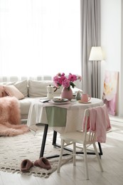 Photo of Beautiful table setting with pink peonies in living room