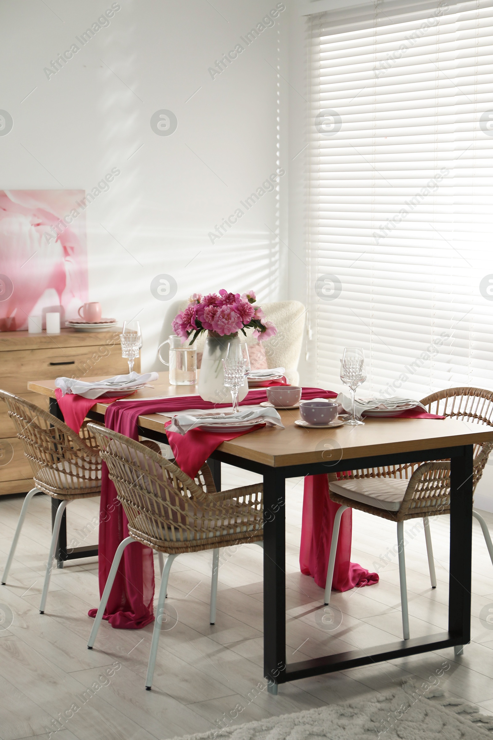 Photo of Pink peonies on table with beautiful setting and rattan chairs in dining room