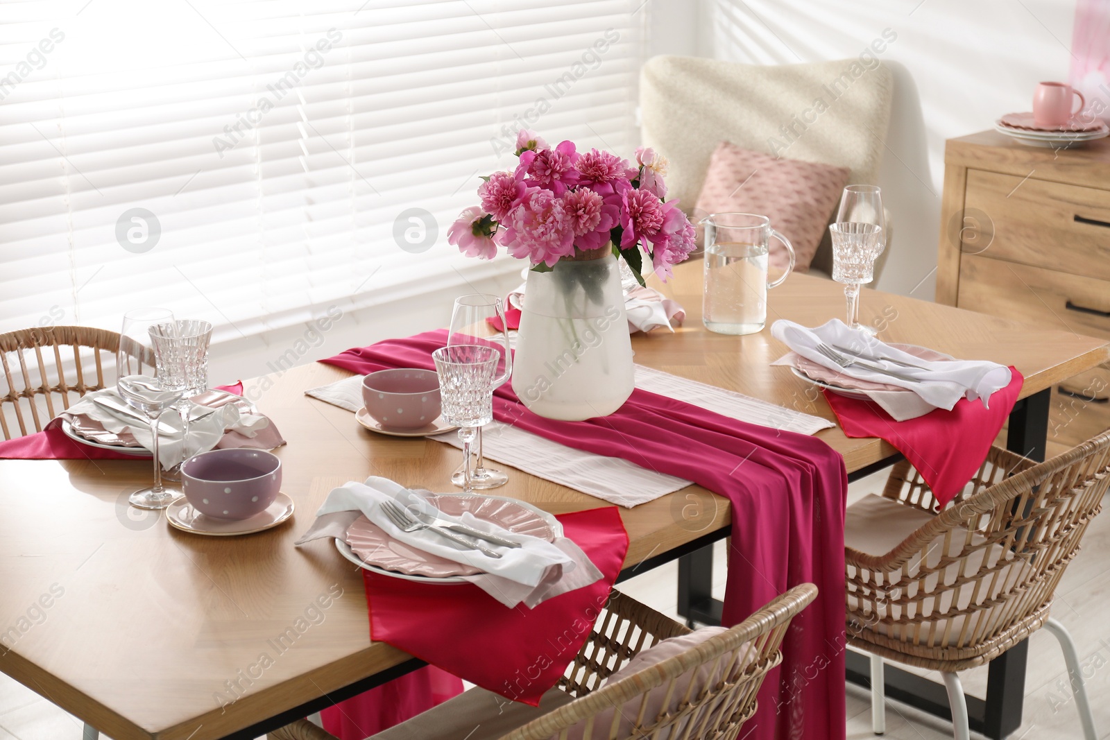 Photo of Pink peonies on table with beautiful setting and rattan chairs in dining room