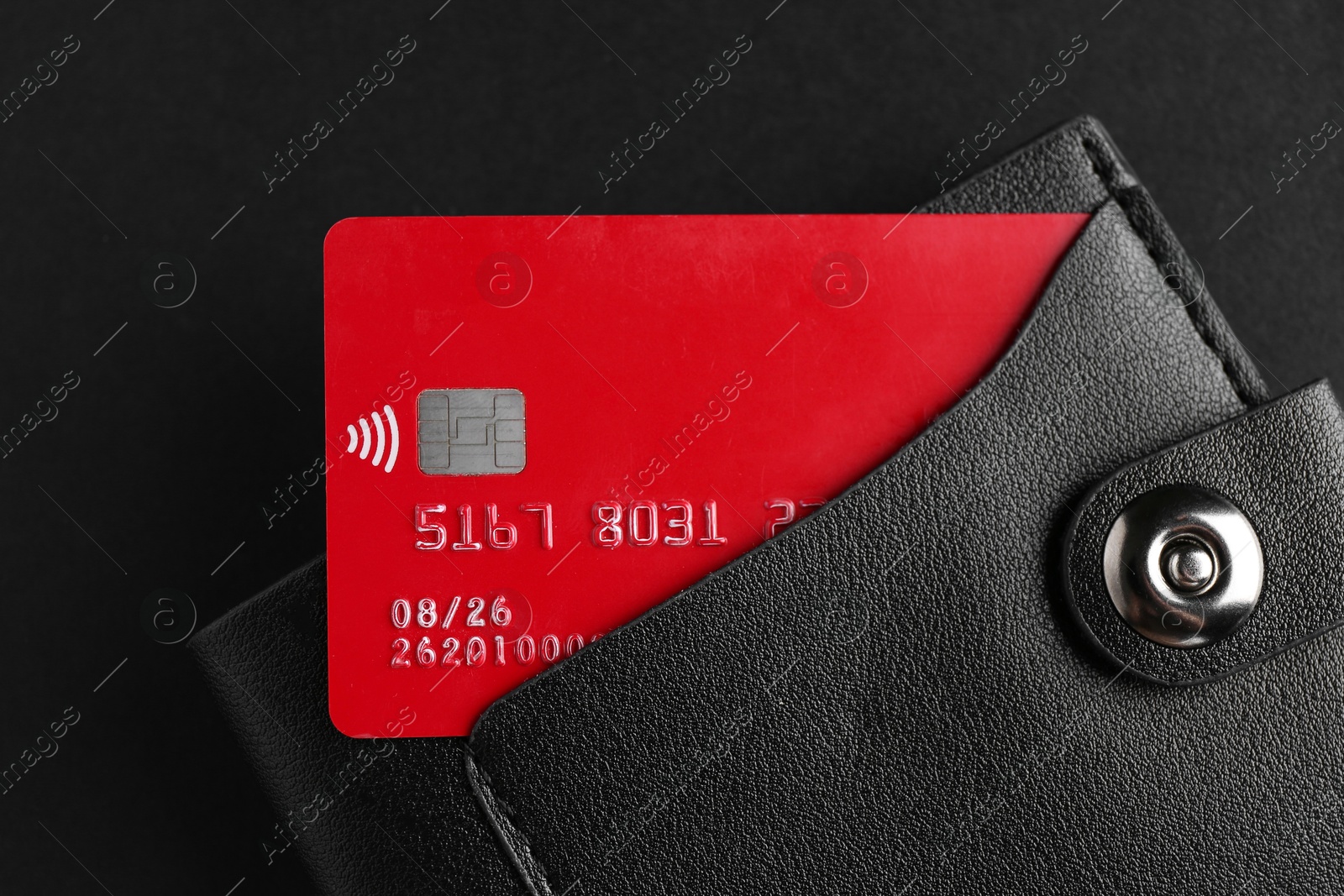 Photo of Credit card in leather wallet on black background, top view