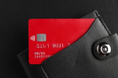 Photo of Credit card in leather wallet on black background, top view