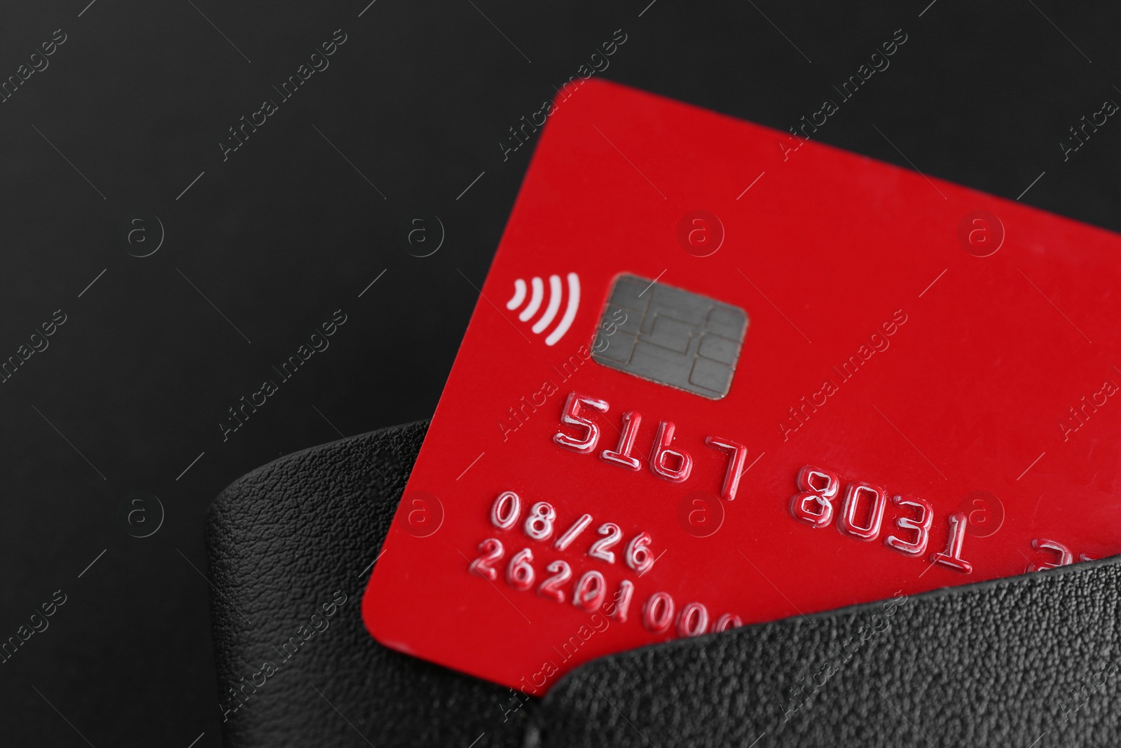 Photo of Credit card in leather wallet on black background, closeup. Space for text